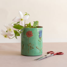Load image into Gallery viewer, Green vase with floral design holding white flowers on a beige surface with scissors.