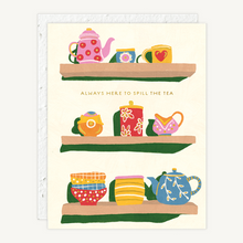 Load image into Gallery viewer, A greeting card featuring three illustrated shelves of teapots, cups, and teacups with the text 'ALWAYS HERE TO SPILL THE TEA'. The card is shown with a white envelope behind it on a light neutral background.