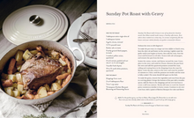 Load image into Gallery viewer, A printed recipe card for Sunday Pot Roast with Gravy, featuring a photograph of a ceramic pot roaster in use on the left and recipe text on the right. The scene includes a hand placing food into the ceramic pot, with warm lighting and a neutral background.