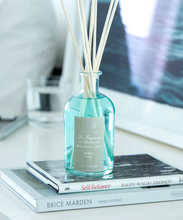Load image into Gallery viewer, antica farmacista 250ml scent diffuser in the acqua scent, a light blue liquid with soft grey label and white reed sticks. styled on two coffee table books in a neutral bedside table background