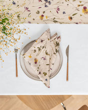 Load image into Gallery viewer, magic linen botnical print natural linen napkin on a place setting folded into a casual triangle on a white plate with feverfew flowers in the foreground and a botanical print linen runner on the table.