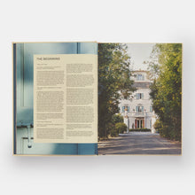 Load image into Gallery viewer, An open book or magazine spread showing a printed article titled "THE BEGINNING" on the left page and a photograph of a large white mansion on a tree-lined path on the right page.