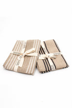 Load image into Gallery viewer, two sets of tea towels, folded and tied with thieffry branded cotton canvas ribbon. one set shown with natural linen with white stripes, the other natural linen with black stripes