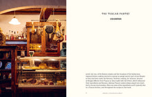 Load image into Gallery viewer, Interior of a rustic kitchen with wooden shelves and hanging lights, featuring text about Tuscan cuisine.

