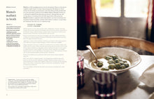 Load image into Gallery viewer, An open cookbook spread showing the recipe for Mama's malfatti in broth on the left page and a photograph of the prepared dish on the right page, with a bowl of green dumplings in broth and a spoon.
