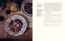 Load image into Gallery viewer, A printed recipe book showing a plated dish of spaghetti with red wine and text titled 'Drunard's spaghetti.' The left page has a food photograph of spaghetti in blue-and-white patterned plates on a rustic table, and the right page contains recipe text.
