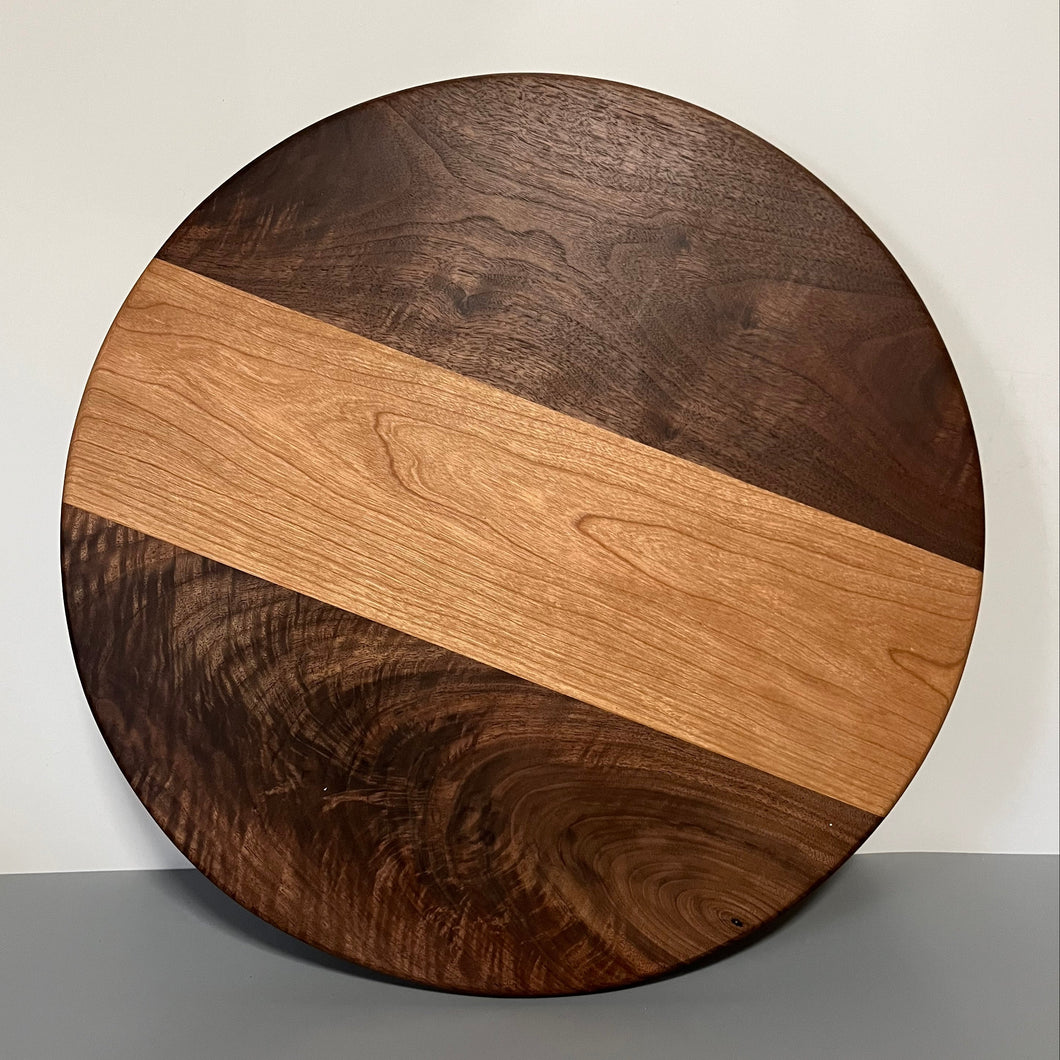 Round wooden cutting board with a two-tone design on a plain background