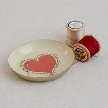 Load image into Gallery viewer, Decorative enamel metal dish with a red heart design, accompanied by spools of thread on a light fabric background.
