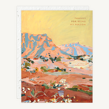 Load image into Gallery viewer, A greeting card featuring an expressive landscape painting of desert mountains and rocky terrain, with the text 'THANKS FOR BEING MY PERSON' in the upper right. The print is shown against a light neutral background with a white envelope visible behind it.
