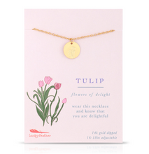 Load image into Gallery viewer, A gold necklace with a round tulip-embossed pendant displayed on a light pink Lucky Feather card labeled 'TULIP'. The card features a pink tulip illustration and text including 'flowers of delight' and 'wear this necklace and know that you are delightful'.

