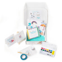 Load image into Gallery viewer, Artistic supplies including watercolor crayons, paint palette, and other stationery items on a white background.
