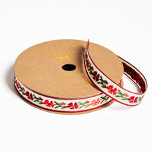 Load image into Gallery viewer, Spool of ribbon with floral pattern on a white background
