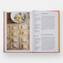 Load image into Gallery viewer, Open cookbook showing a recipe for Sea Bass Ravioli with an image of ravioli on a wooden board.
