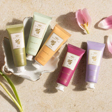 Load image into Gallery viewer, Five Tocca hand cream tubes in different colors on a textured surface with flowers.
